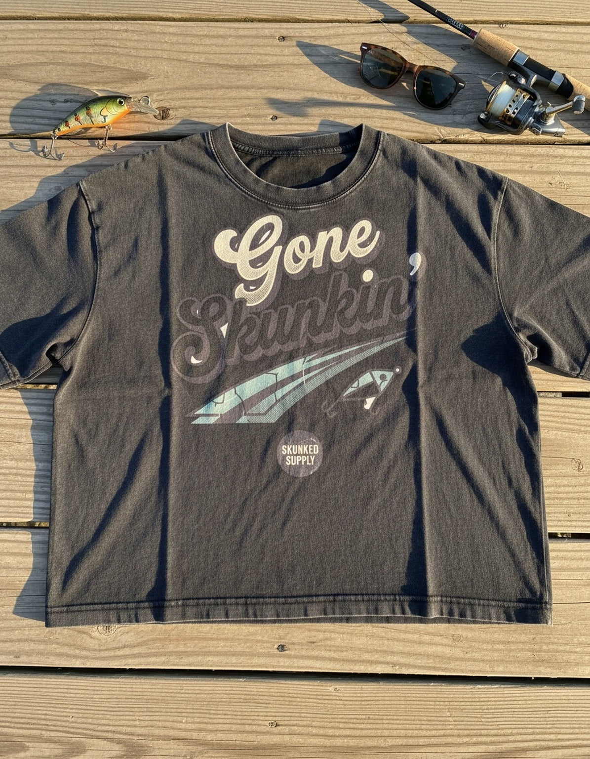 Gone Skunkin' tee on the dock with fishing gear